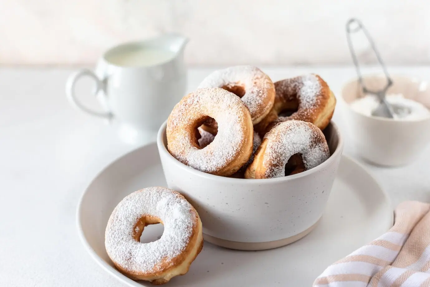 Традиционный завтрак — пончик с сахаром и молоко или кофе на белом фоне, селективная фокусировка.